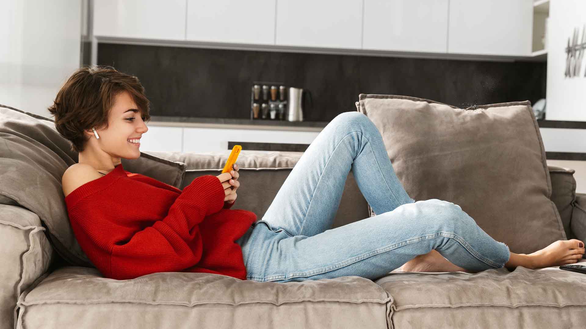 Girl on Sofa Looking at mobile phone